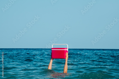 man carrying a cooler while is submerged into the ocean photo