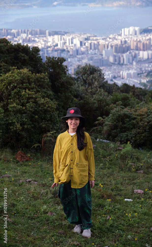 Asian girl on a mountain with a panoramic view of the city background