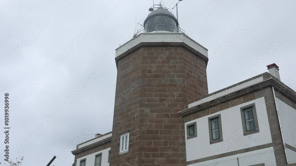 Rustic stone lighthouse building under overcast skies seen from a low angle view Rustic stone lighthouse building under overcast skies seen from a low angle view