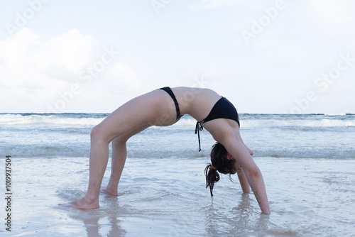 Young woman practising yoga on the beach photo