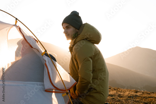 Man prepare outdoor tent before sleeps in sunrset. photo