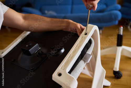 A Young Man Assembling a Stylish Modern Chair in a Comfortable Minimalist Interior Space