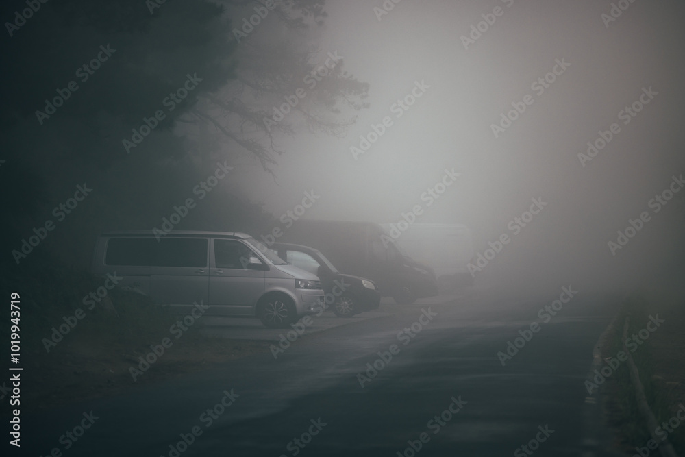Vehicles parked in foggy terrain creating an eerie atmosphere Vehicles parked in foggy terrain creating an eerie atmosphere