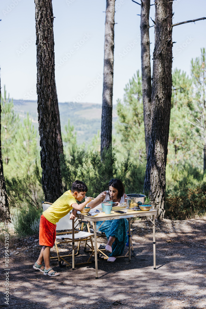 Mother and child enjoying a meal in a sunny forest setting Mother and child enjoying a meal in a sunny forest setting