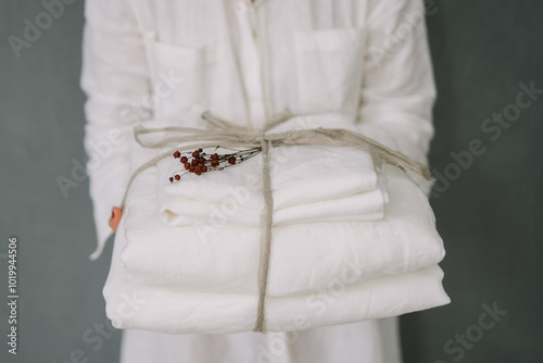 A person holding white folded linens tied with string. photo