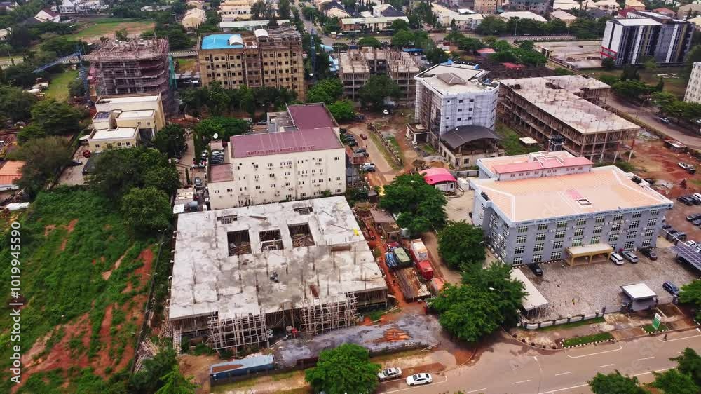 Aerial of a residential area in Abuja, Nigeria. A large building is under construction. The drone slowly flies backwards Aerial of a residential area in Abuja, Nigeria. A large building is under construction. The drone slowly flies backwards