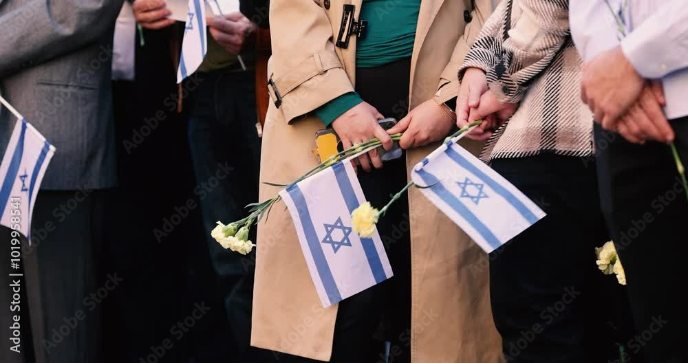 People hold the Israeli flag and flowers during a ceremony commemorating the October 2023 attacks on Israel.