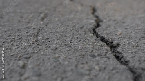 Close-up of asphalt texture with deep cracks. Part of the video is out of focus. Moving forward. Dry old cracked asphalt surface. High quality 4k footage