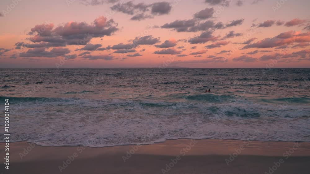 Experience the Serene Beach Sunset characterized by Gentle Waves and a Beautiful Pink Sky Experience the Serene Beach Sunset characterized by Gentle Waves and a Beautiful Pink Sky