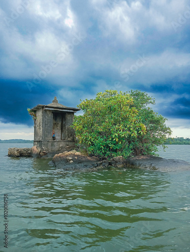 Unique Satha Paha Island on Madu River, Sri Lanka with Sacred Shrine and Lush Foliage Surrounded by Calm Waters - Stunning Isolated Island under Dramatic Cloudy Sky photo