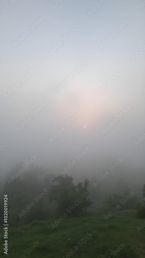 Naklejka premium A tranquil scene of a misty sky at dawn, with the landscape partially obscured by fog and the soft light of morning breaking through