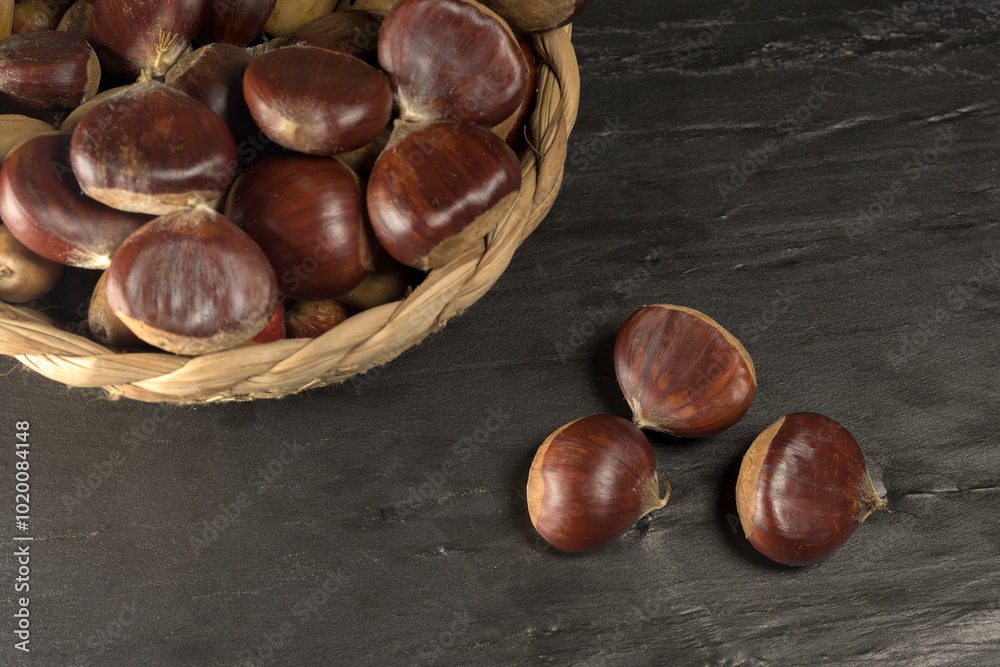 Chestnuts and autumn leaves on black background Chestnuts and autumn leaves on black background
