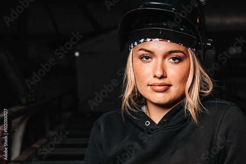 Woman in work gloves and welding helmet, holding a torch in a workshop photo