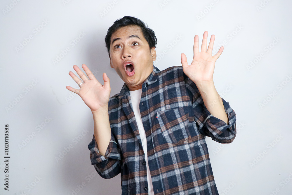 Excited Asian man gasping with hands open and looking to copy space isolated on yellow background Excited Asian man gasping with hands open and looking to copy space isolated on yellow background