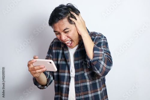 Oh No. Portrait of emotional shocked asian guy holding and using smartphone, seeing surprising news, photos or message. Surprised man grabbing head isolated over white studio background wall