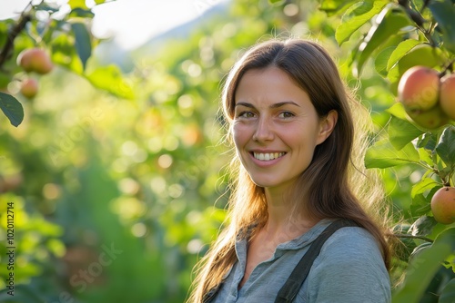 A woman is smiling in front of a tree with apples. Concept of happiness and contentment