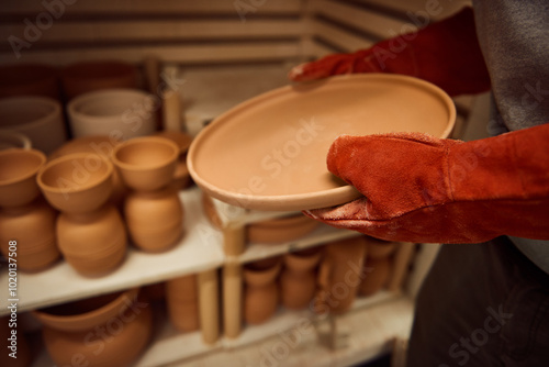 Bild auf Leinwand Ceramist removing a clay plate from a kiln in his workshop