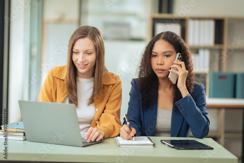 Two female colleagues discussing company business work using laptops and their emphatic expressions suggest that they are discussing important business matters.