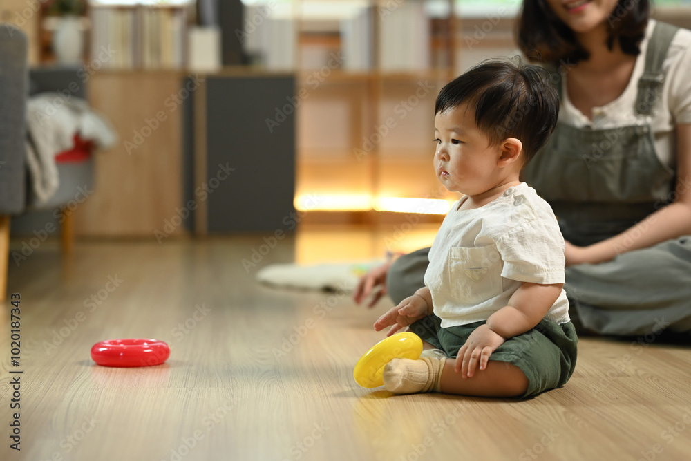 Little toddler boy playing with toys on wooden floor at home. Child development and learning concept Little toddler boy playing with toys on wooden floor at home. Child development and learning concept