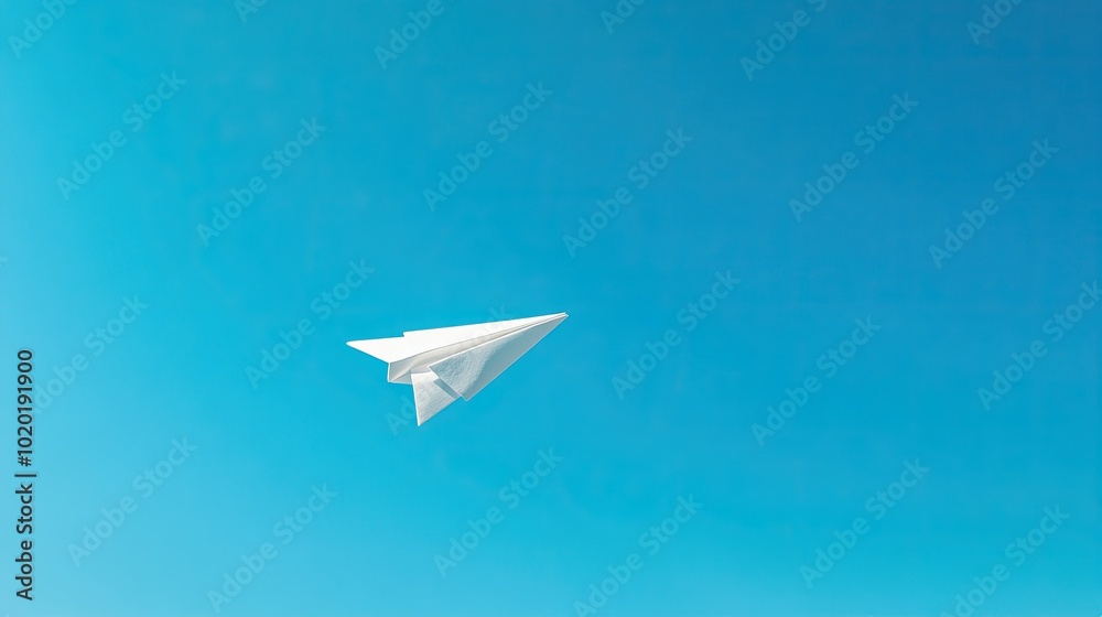 A white paper plane flying through the air in front of a bright blue sky. A white paper plane flying through the air in front of a bright blue sky.