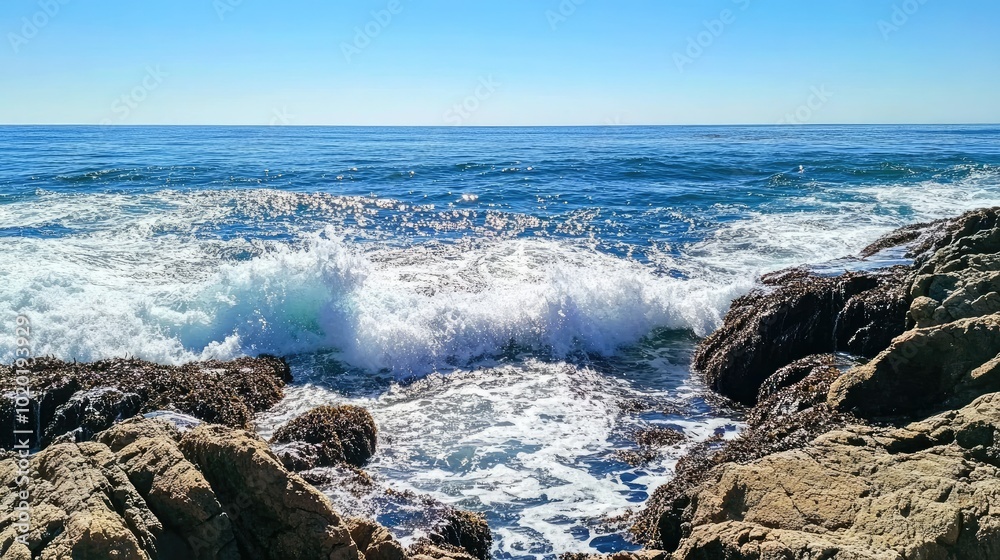 Deep blue ocean waves crashing against a rocky shore under a clear sky. Deep blue ocean waves crashing against a rocky shore under a clear sky.