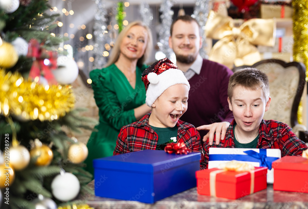 Children and parents give each other gift boxes during Christmas or New Year celebrations at home Children and parents give each other gift boxes during Christmas or New Year celebrations at home