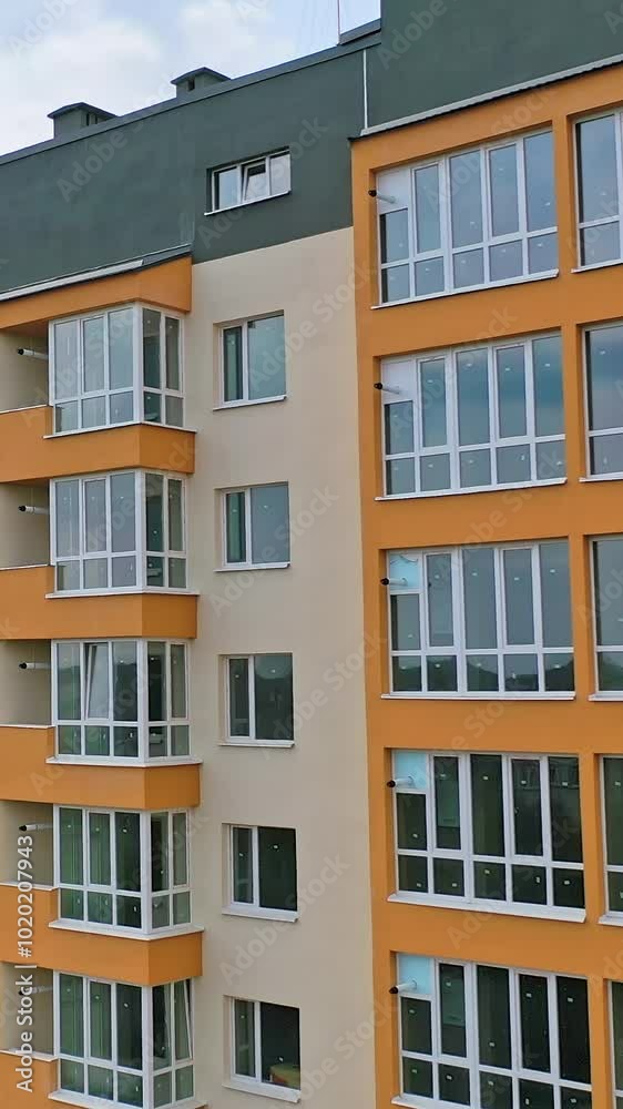 Construction of a modern building in the city. Facade of multistory apartment house with plastic windows in the city. Building of a new architecture concept Vertical video Construction of a modern building in the city. Facade of multistory apartment house with plastic windows in the city. Building of a new architecture concept Vertical video