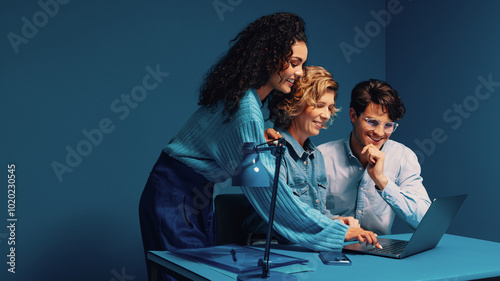 Group of colleagues collaborating on a laptop in colorful office