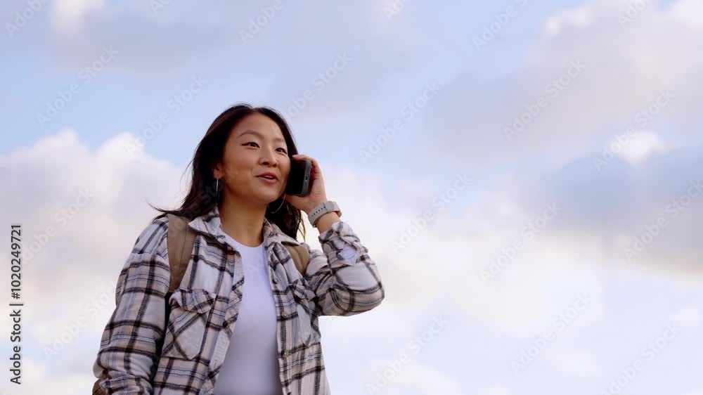 Young Asian woman talking on phone. There is copy space in the sky. Young Asian woman talking on phone. There is copy space in the sky.