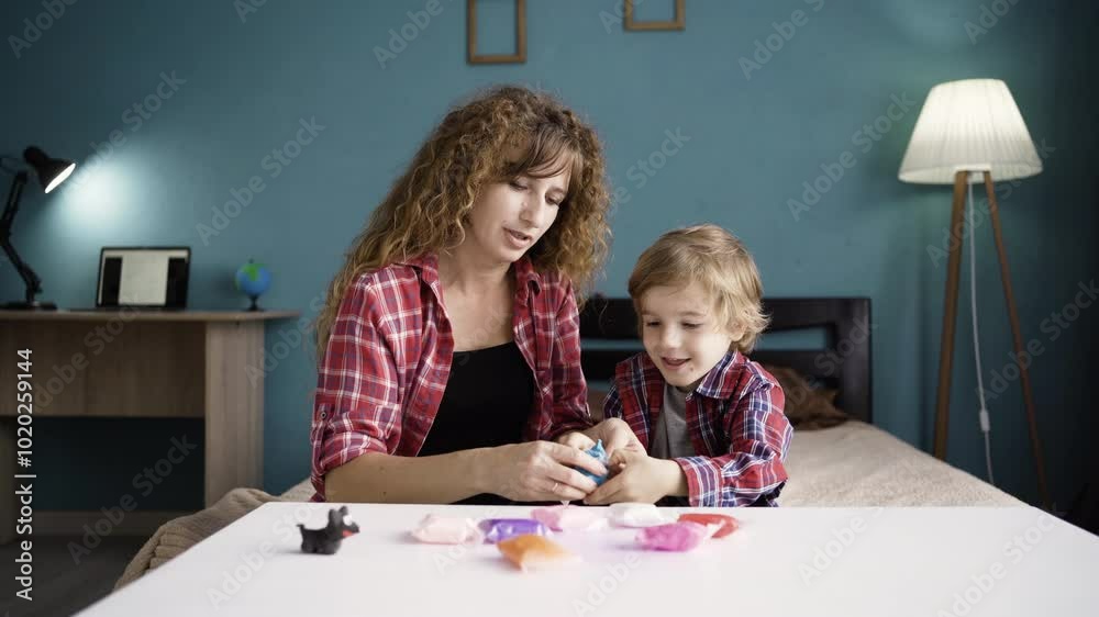 Mother with her little son unpacked plasticine. Woman and boy mold from plasticine in the living room