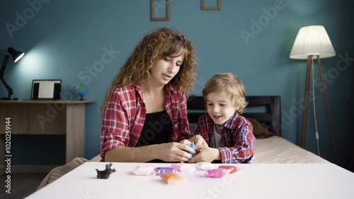 Mother with her little son unpacked plasticine. Woman and boy mold from plasticine in the living room