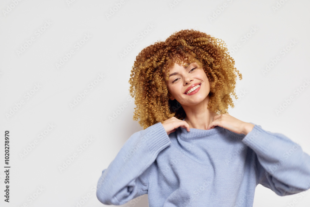Smiling woman with curly hair wearing a blue sweater against a plain white background, exuding joy and confidence with a warm, engaging expression, perfect for lifestyle imagery Smiling woman with curly hair wearing a blue sweater against a plain white background, exuding joy and confidence with a warm, engaging expression, perfect for lifestyle imagery