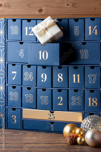 Advent calendar, blue boxes with numbers with gift and Christmas balls on a wooden background. Waiting, Christmas countdown. Vertical orientation.