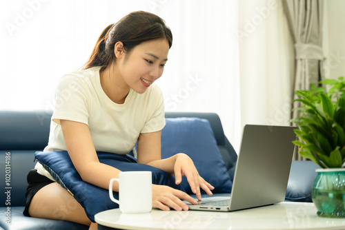 Portrait of young Asian girl using laptop and drink coffee , at home