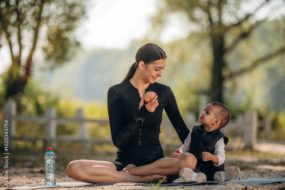 Yoga day, sitting. Mother with her little son is outdoors. In sportive clothes Yoga day, sitting. Mother with her little son is outdoors. In sportive clothes
