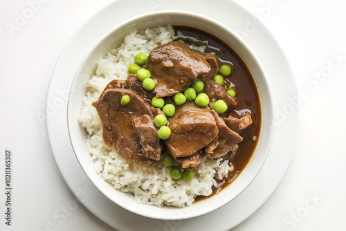 A bowl of a braised pork or beef stew with green peas, served over cooked white rice