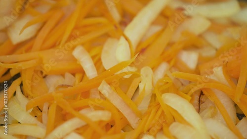 Frying onions and carrots in a frying pan.