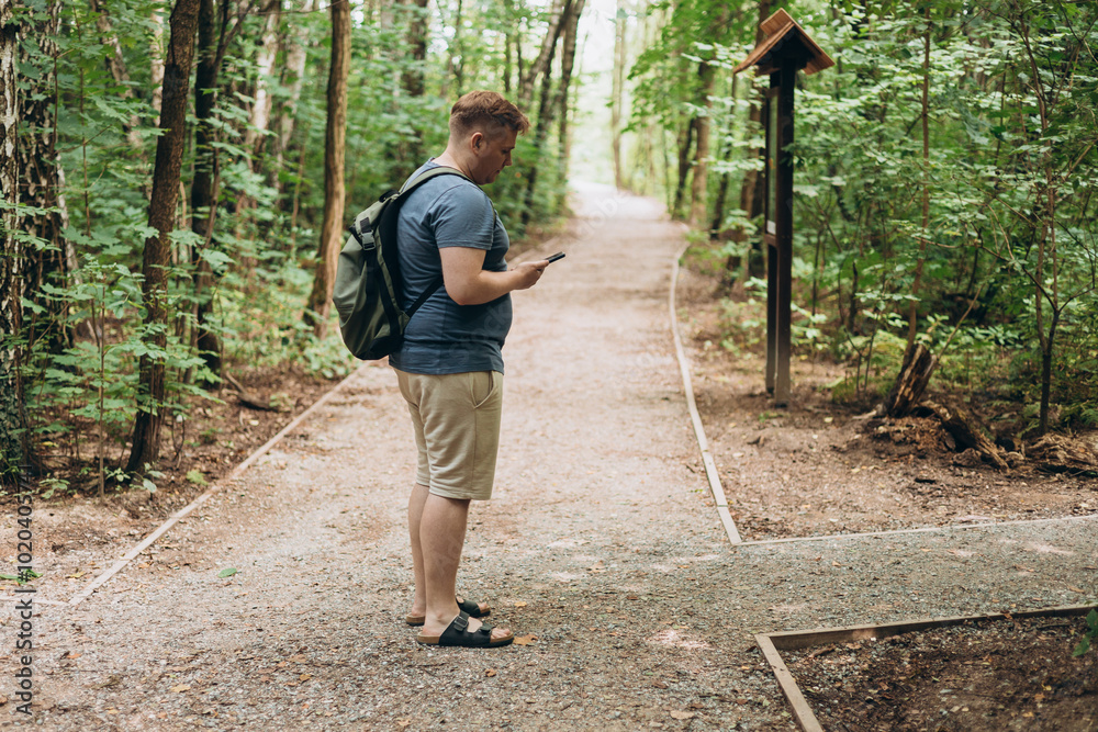 Happy hiker man with backpack using mobile phone while relaxing in nature. Travel and adventure concept, full body Happy hiker man with backpack using mobile phone while relaxing in nature. Travel and adventure concept, full body