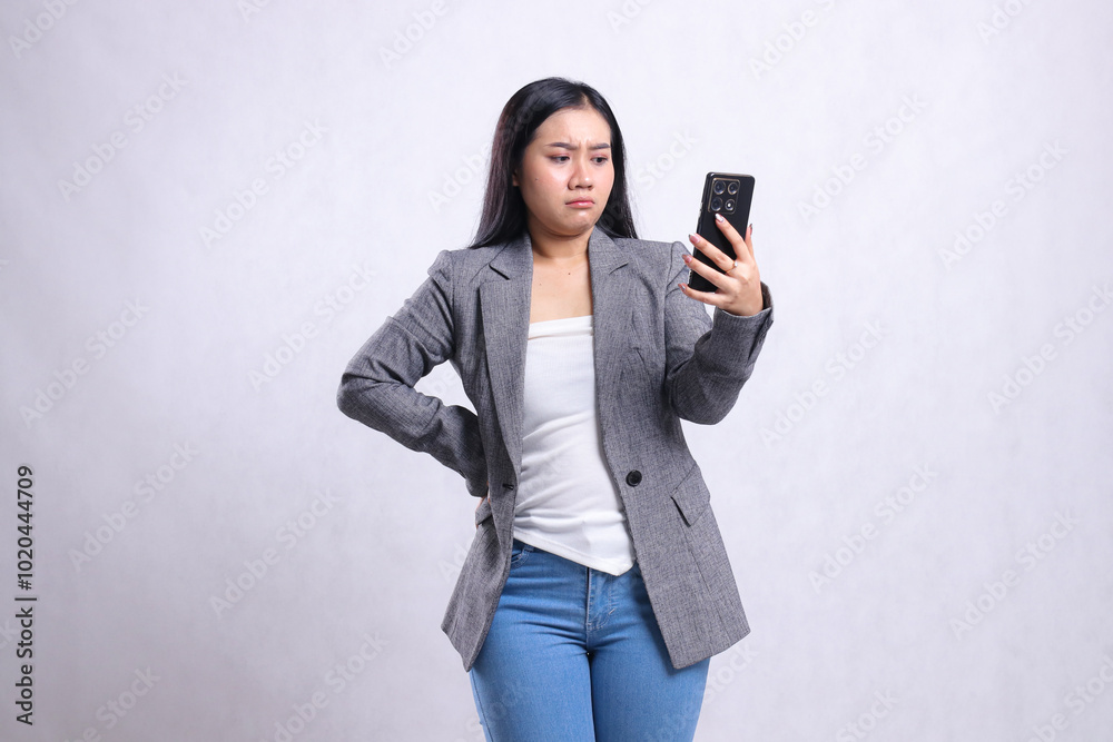 beautiful adult office girl asia sad to mobile phone hold waist, holding cellphone wearing gray suit isolated on white background. for technology, lifestyle, shopping, transaction content beautiful adult office girl asia sad to mobile phone hold waist, holding cellphone wearing gray suit isolated on white background. for technology, lifestyle, shopping, transaction content
