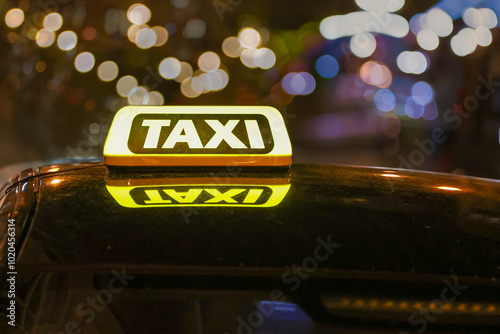 Close-up view of a brightly illuminated yellow taxi sign on the roof of a vehicle.