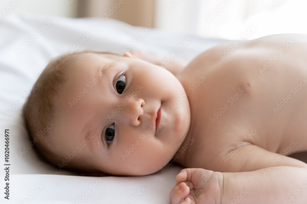 Cute infant baby girl or boy looking at camera with curious eyes