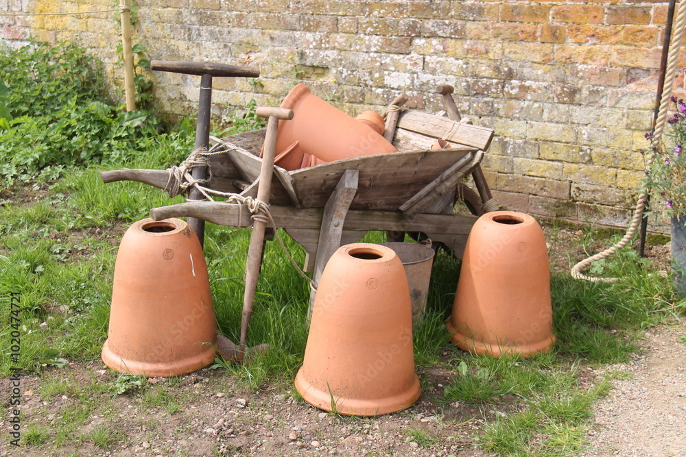 Obraz premium A Wheelbarrow Display with Tools and Terracotta Pots.