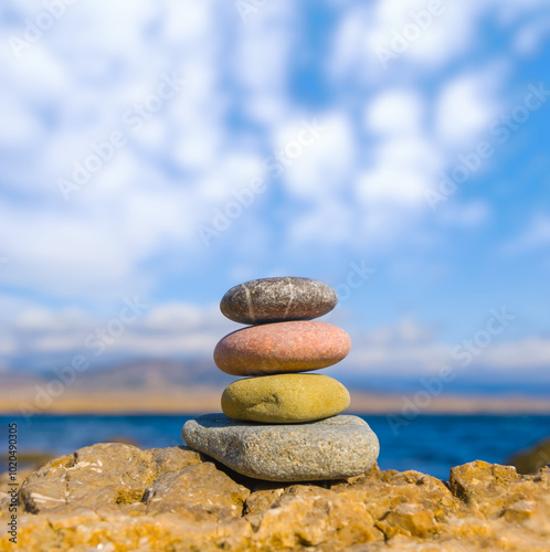 heap of varicoloured sea stones on a coast under blue cloudy sky