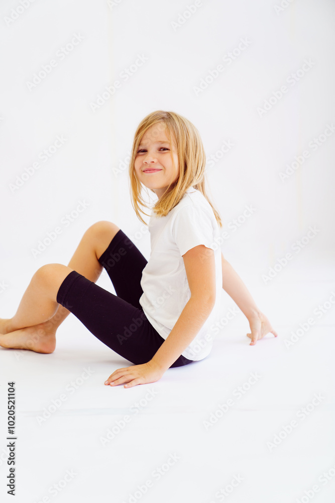 Fototapeta premium Cheerful teenage girl in white t-shirt and black breeches on white background