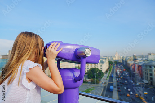 a teenage girl looks into the Binoscope from the observation deck at a height.  photo