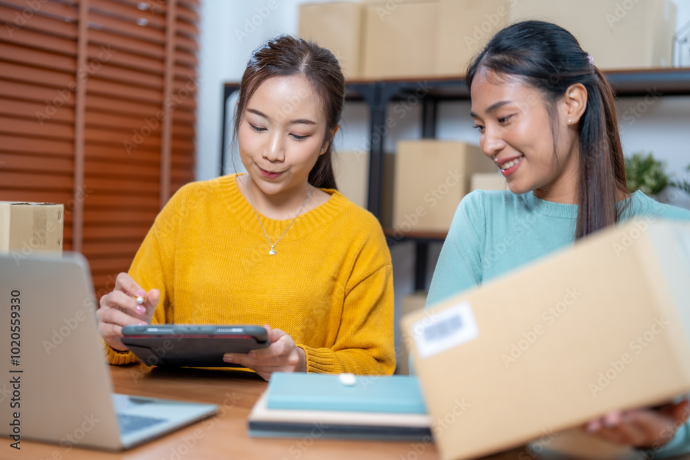 Young Entrepreneurs Managing Online Clothing Store from Home with Digital Devices and Packaging for Shipment Young Entrepreneurs Managing Online Clothing Store from Home with Digital Devices and Packaging for Shipment