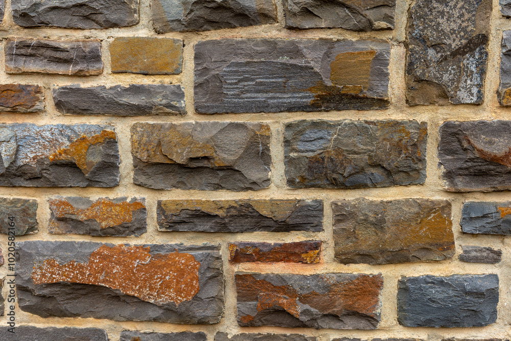 Fototapeta premium A close-up of a stone wall with brown and gray stones and tan mortar