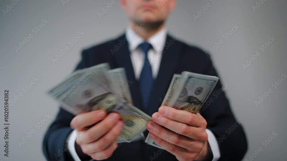 Formally dressed man is counting US Dollar bills, close-up.