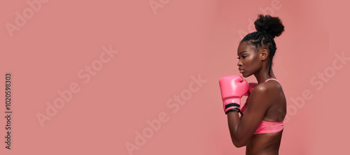 A black woman wearing pink boxing gloves in front of a pink background. Generative AI