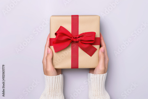 Gift Giving: A pair of hands in a cozy sweater hold a beautifully wrapped gift, tied with a vibrant red ribbon. It's a simple yet heartfelt gesture of love, appreciation, and celebration. 